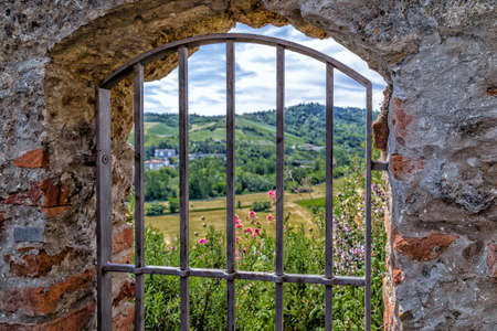 Medieval window with iron grating overlooking the countryside of Romagna in Italyの写真素材