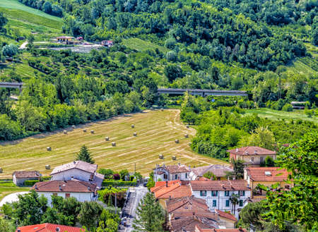 yellow round hay bales spread in cultivated fields in the Italian countrysideの写真素材