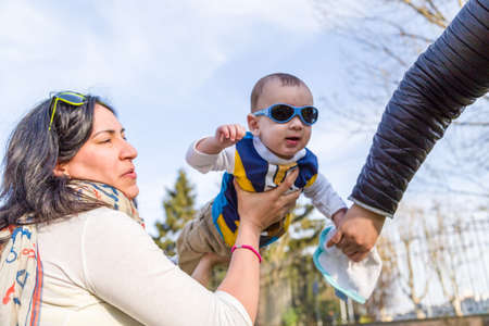 Cute 6 months old baby with Light brown hair in white, blue and brownish long-sleeved shirt wearing...