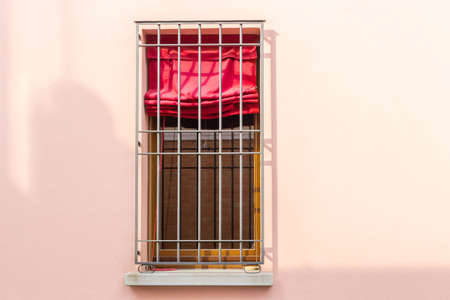 Iron grating window with red curtain
