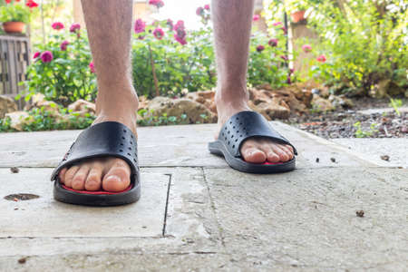 Bare feet of boy in black slippers with hairy legs in your back yardの写真素材