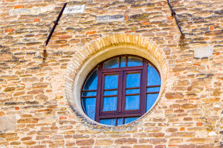 Round window on ancient brick wall of Catholic church in Italian countrysideの写真素材