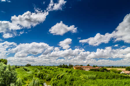 river in the countryside in the north of Italy under a cloudy blue skyの写真素材