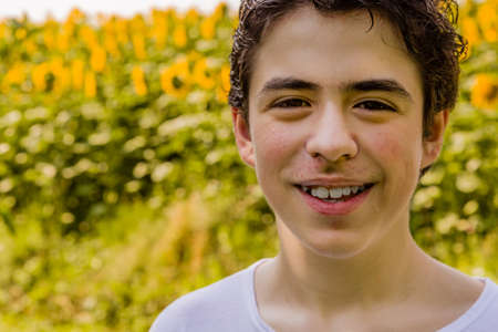 Natural and healthy living - Caucasian boy smiling in front of a field of sunflowers