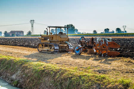 old tractor is plowing a field in Italian countrysideの写真素材