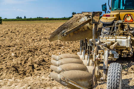 the peaceful silence of the fields in the Emilia Romagna region in the lower Po valley in Italy while a tractor is parked in front of the plowed fieldの写真素材