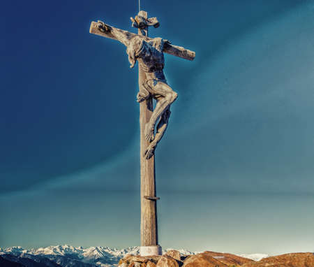 A wood carved statue  of the Crucifixion of Jesus Christ on top of the dolomites alpsの写真素材