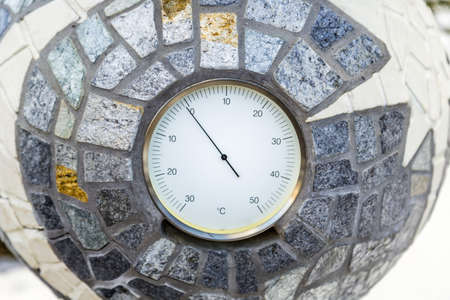 Temperature just below zero Celsius marked by a analogue environmental  thermometer cemented into a...