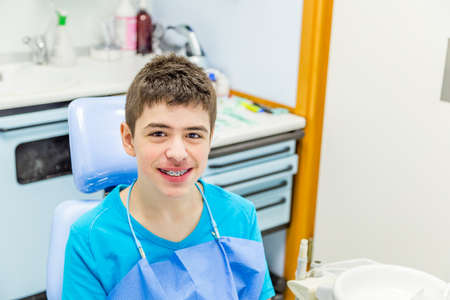 teenager with braces sitting in the chair of the dentist and calmly waiting for the medical dentistの写真素材