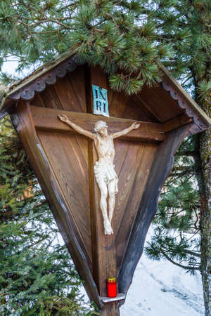 votive edicola with crucifix under conifer in the snowy Alpsの写真素材