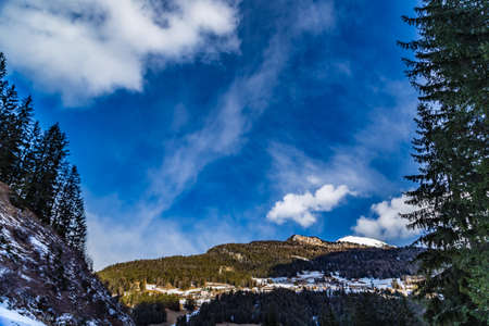 Dolomite mountains covered with white snow and green conifers in Italy
