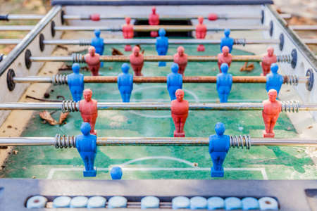 details of red and blue table football dummy players, dirty and rusty, covered with leaves and dustの写真素材