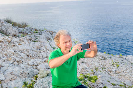 Handsome man in green polo takes a selfie in a seaside town