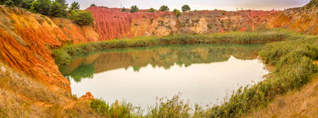 red soils around the freshwater lake formed in a former quarry for the extraction of bauxite in Italyの写真素材