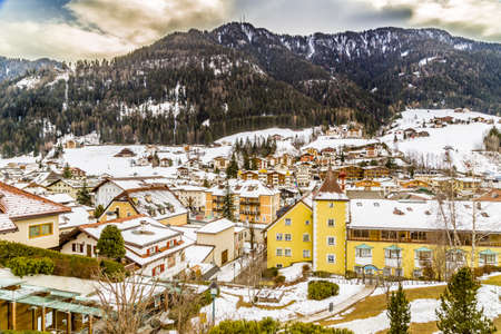 Snowy alpine village in Italy illuminated by sun with mountains in the backgroundの写真素材