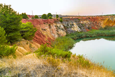 red soils around the freshwater lake formed in a former quarry for the extraction of bauxite in Italyの写真素材