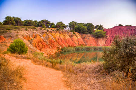 red soils around the freshwater lake formed in a former quarry for the extraction of bauxite in Italyの写真素材