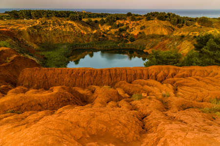 red soils around the freshwater lake formed in a former quarry for the extraction of bauxite in Italyの写真素材