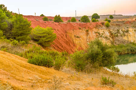 red soils around the freshwater lake formed in a former quarry for the extraction of bauxite in Italyの写真素材