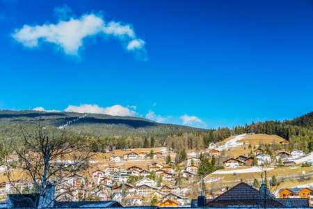 Snowy alpine village in Italy illuminated by sun with mountains in the backgroundの写真素材