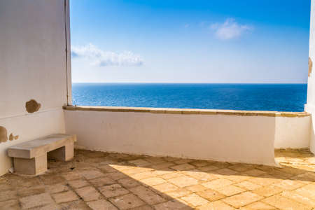 stone bench and parapet on steep cliffs above the sea along the coast of Puglia in Italyの写真素材