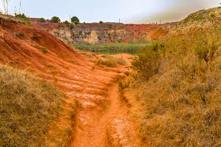 red soils around the freshwater lake formed in a former quarry for the extraction of bauxite in Italyの写真素材