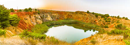 red soils around the freshwater lake formed in a former quarry for the extraction of bauxite in Italyの写真素材