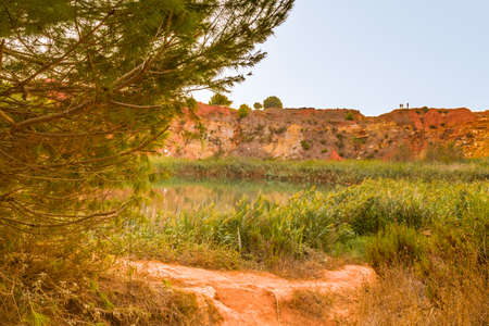 red soils around the freshwater lake formed in a former quarry for the extraction of bauxite in Italyの写真素材