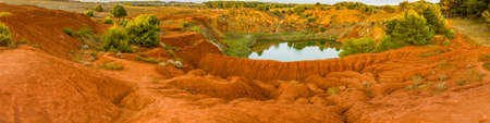 red soils around the freshwater lake formed in a former quarry for the extraction of bauxite in Italyの写真素材