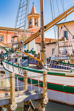Church and ancient boats on Canal Port in Cesenaticoの写真素材