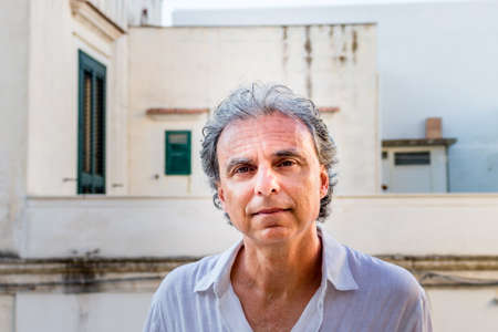 middle-aged man in white shirt while visiting the old streets of ancient town, Vieste in Italy,...