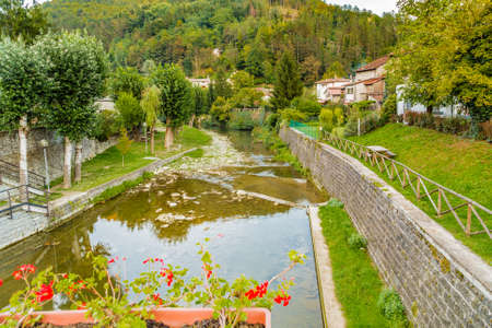 River runs thorugh medieval mountain village in Tuscany characterized by houses with walls of stones derived from the Renaissanceの写真素材