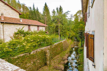 Small stream runs trhough medieval mountain village in Tuscany characterized by houses with walls of stones derived from the Renaissanceの写真素材