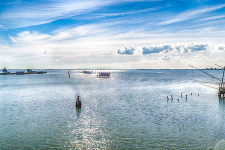 fishing huts with balance netfish and seagull on pole in the lagoon of the valleys of Comacchio in Emilia Romagnaの写真素材