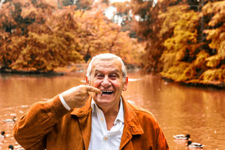 senior with suede jacket and white shirt in a green park indicates denturesの写真素材