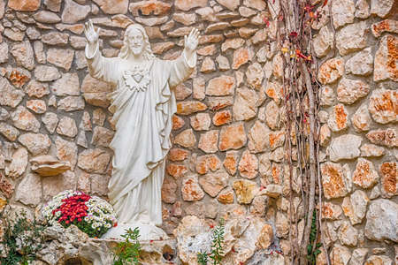 Sacred Heart of Jesus white statue in front of brick stone wallsの写真素材