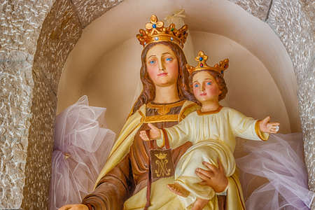 Statue of the Blessed Virgin Mary with Baby Jesus on stone wallsの写真素材