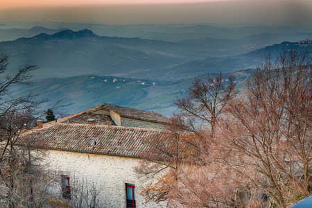 Roofs of houses of the Republic of San Marino in a winter sunset over the foggy valley