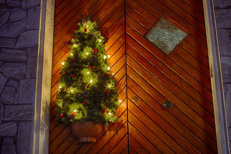 Christmas tree with Christmas lights to decorate a wooden door of houseの写真素材