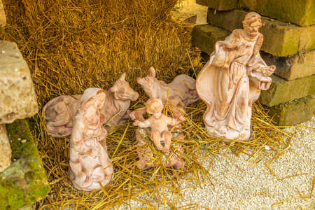 Statues in a Christmas Nativity scene, the Blessed Virgin Mary and Saint Joseph watch over the Holy Child Jesus in a manger in the straw as the ox and the donkey are warmingの写真素材