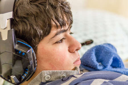 boy with wearing headphones while playing with video gamesの写真素材