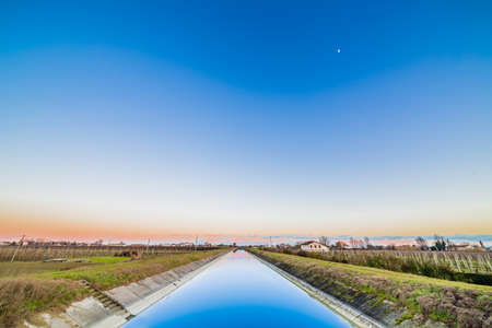 artificial water canal to irrigate the cultivated fields in the countryside of Emilia Romagna in Italyの写真素材