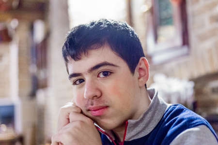 teenager pensive and brooding at the restaurant is holding his head with one hand