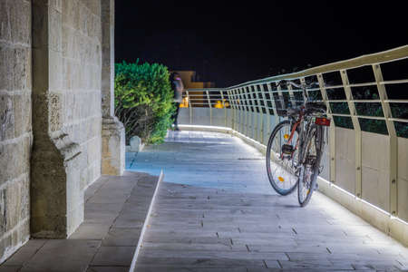 bicycle leaning against a lit railing in front of an old church at nightの写真素材