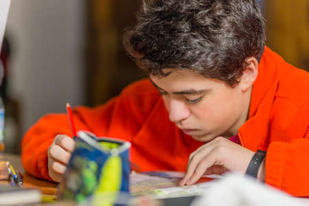 caucasian boy doing homeworks writes with red and blue pencilの写真素材