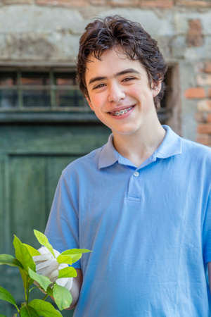 teenager with braces while taking care of a lemon tree holding green leaves with latex glovesのeditorial素材