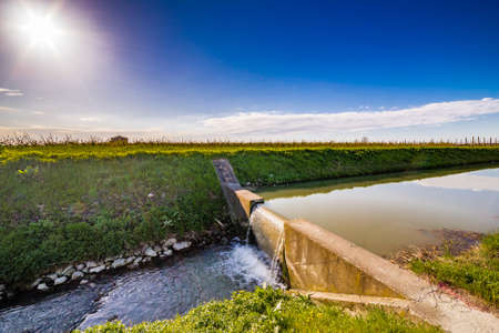 Modern irrigation canal that runs through the cultivated fields of Emilia Romagna in Italyの写真素材