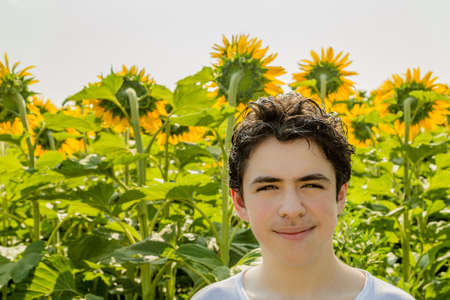 Natural and healthy living - Caucasian boy smiling in front of a field of sunflowersの写真素材