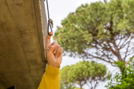 finger pulling the eyelet of a nylon cord under a balcony in the garden