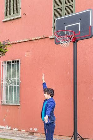 boy training defensive positions in a basketball grunge playground near the peeling wall of an old...